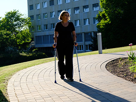 Bild Patientin läuft auf Gehhilfen durch den Park