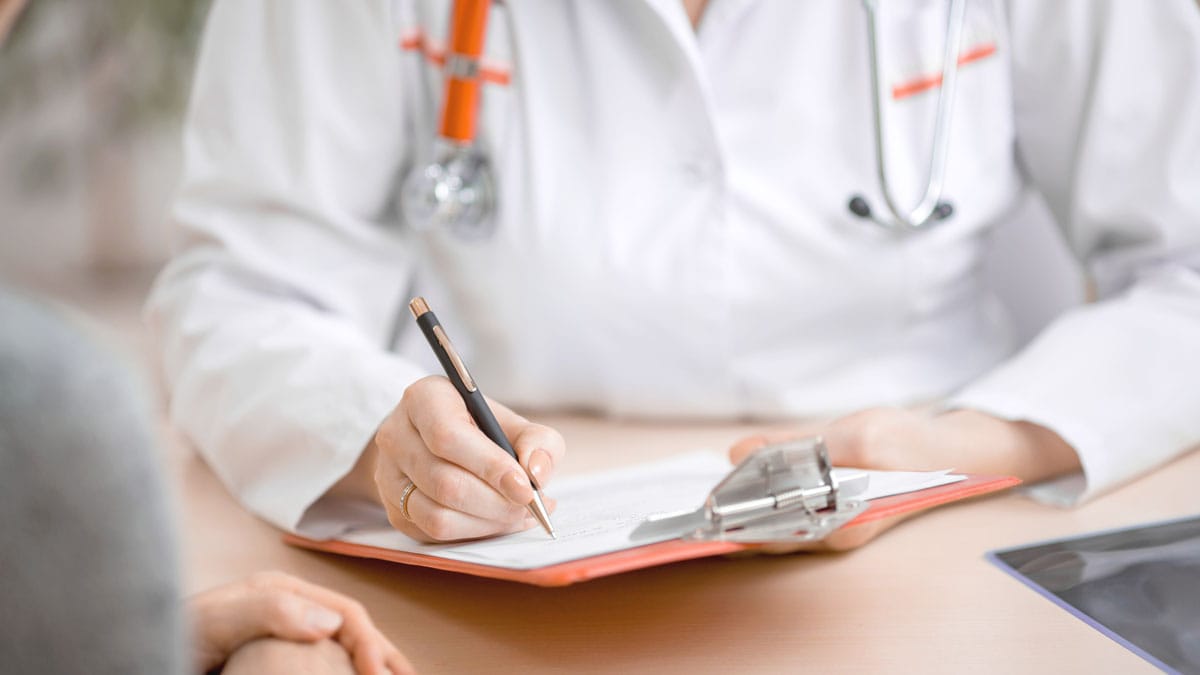 Bild Ärztin füllt ein Formular aus das auf einem Klemm Brett liegt